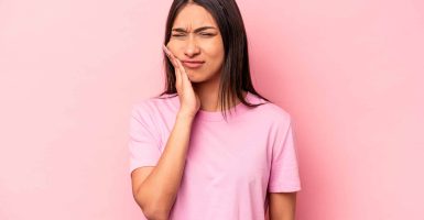 Young hispanic woman isolated on pink background having a strong teeth pain, molar ache.