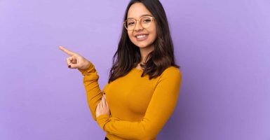 Young mixed race woman isolated on purple background pointing finger to the side