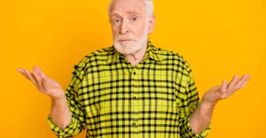 Photo of old man pensioner shrug shoulders confused questioned no answer isolated over yellow color background.