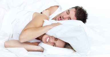 Couple in bed while the woman is trying to sleep and the man is snoring